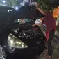 Ardi terus memperbaiki mobil mogok akibat terendam banjir (Hermawan Arifianto/Liputan6.com)