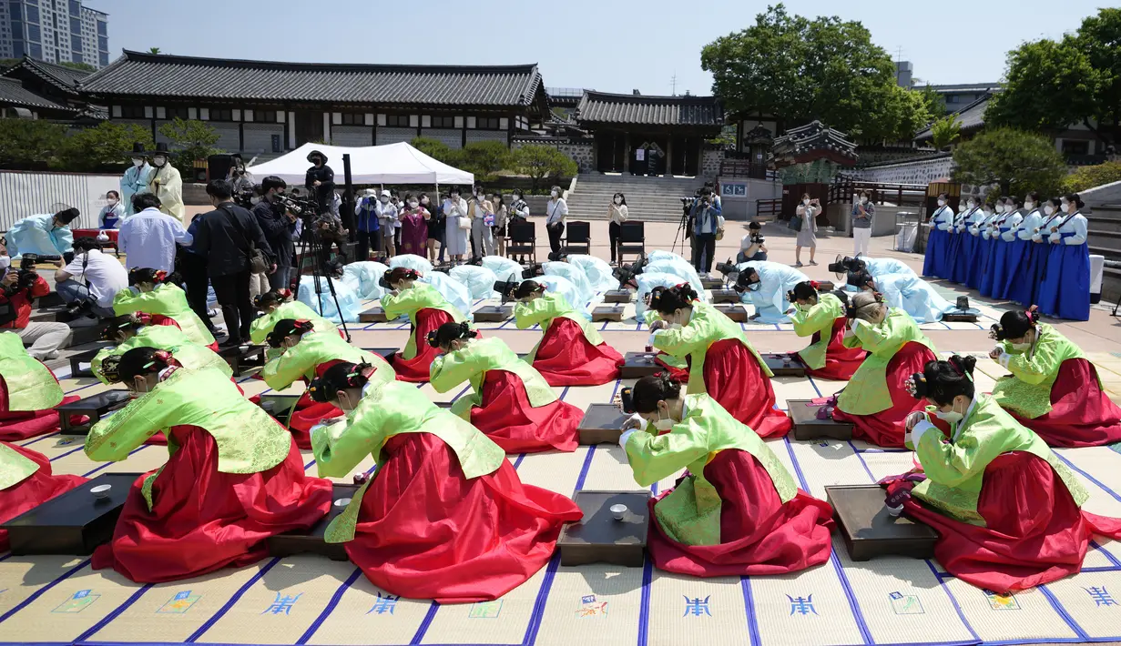 Wanita dan pria mengenakan gaun tradisional Korea Selatan membungkuk selama upacara untuk menghidupkan kembali Hari Kedewasaan ke-50 di Desa Hanok Namsangol di Seoul, Korea Selatan (16/5/2022). Upacara diadakan untuk pria dan wanita muda yang akan berusia 20 tahun. (AP Photo/Lee Jin-man)