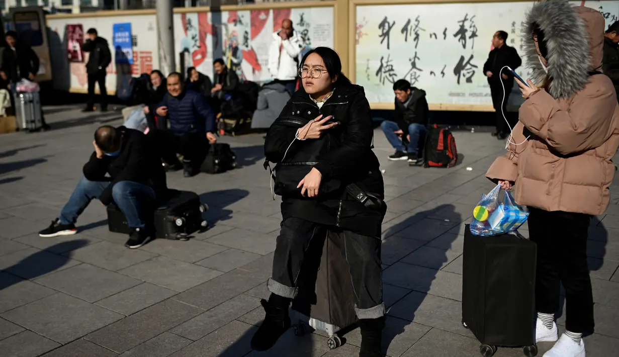 Calon pemudik menunggu jadwal keberangkatan kereta mereka di luar pintu masuk stasiun Beijing, Jumat (10/1/2020). Puluhan ribu warga China telah meninggalkan kota-kota besar China menuju kampung halaman, guna merayakan Tahun Baru Imlek yang akan jatuh pada 25 Januari mendatang. (WANG ZHAO/AFP)