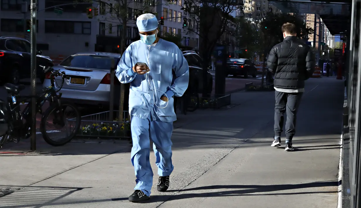Seorang pekerja medis berjalan sambil melihat ponsel menuju rumah sakit selama pandemi COVID-19 di New York City (21/4/2020). (Cindy Ord/Getty Images/AFP)