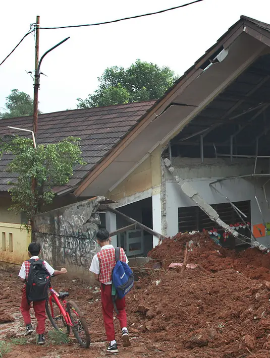 Murid melintas di dekat kelas SDN Bambu Apus 1 usai tertimpa truk pengangkut tanah proyek Tol Cinere-Serpong di Kelurahan Bambu Apus, Kecamatan Pamulang, Tangerang Selatan, Senin (14/1). Kejadian tersebut terjadi Minggu (13/1). (Merdeka.com/Arie Basuki)