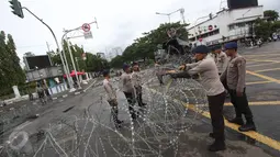Aparat kepolisian memasang kawat berduri di sekitar Istana Negara, Jakarta, Jumat (31/3). Kawat berduri tersebut dipasang untuk mengantisipasi ricuh aksi 31 Maret. (Liputan6.com/Immanuel Antonius)