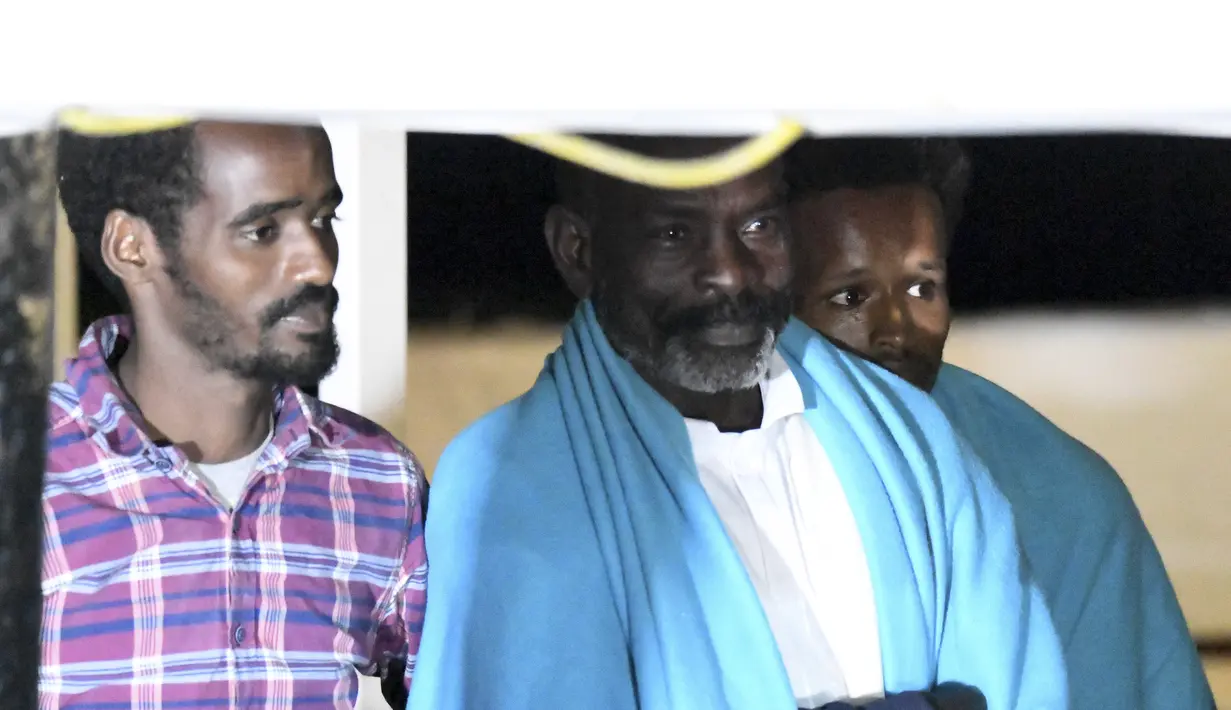 Ekspresi para migran saat berdiri di atas kapal penyelamat Open Arms sebelum turun di pulau Lampedusa di Sisilia, Italia selatan (20/8/2019). Setidaknya 15 migran lainnya melompat ke laut dari kapal Open Arms untuk menuju pantai Italia. (AP Photo/Francisco Gentico)