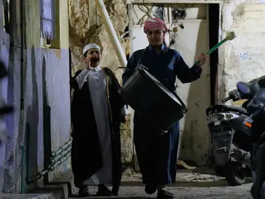 Wissam Ali (kanan), seorang "mesaharati" atau penyeru subuh berusia 22 tahun, saat membangunkan orang-orang untuk makan sebelum matahari terbit, selama bulan suci Ramadan, di lingkungan miskin distrik Fadhil di Baghdad, Irak, Senin 23 Februari 2026. Mesaharati (juga dikenal sebagai Al-Mesaharati) merupakan sebutan bagi seseorang yang bertugas membangunkan umat Muslim untuk makan sahur sebelum waktu Subuh tiba selama bulan Ramadan. (AP Photo/Hadi Mizban)