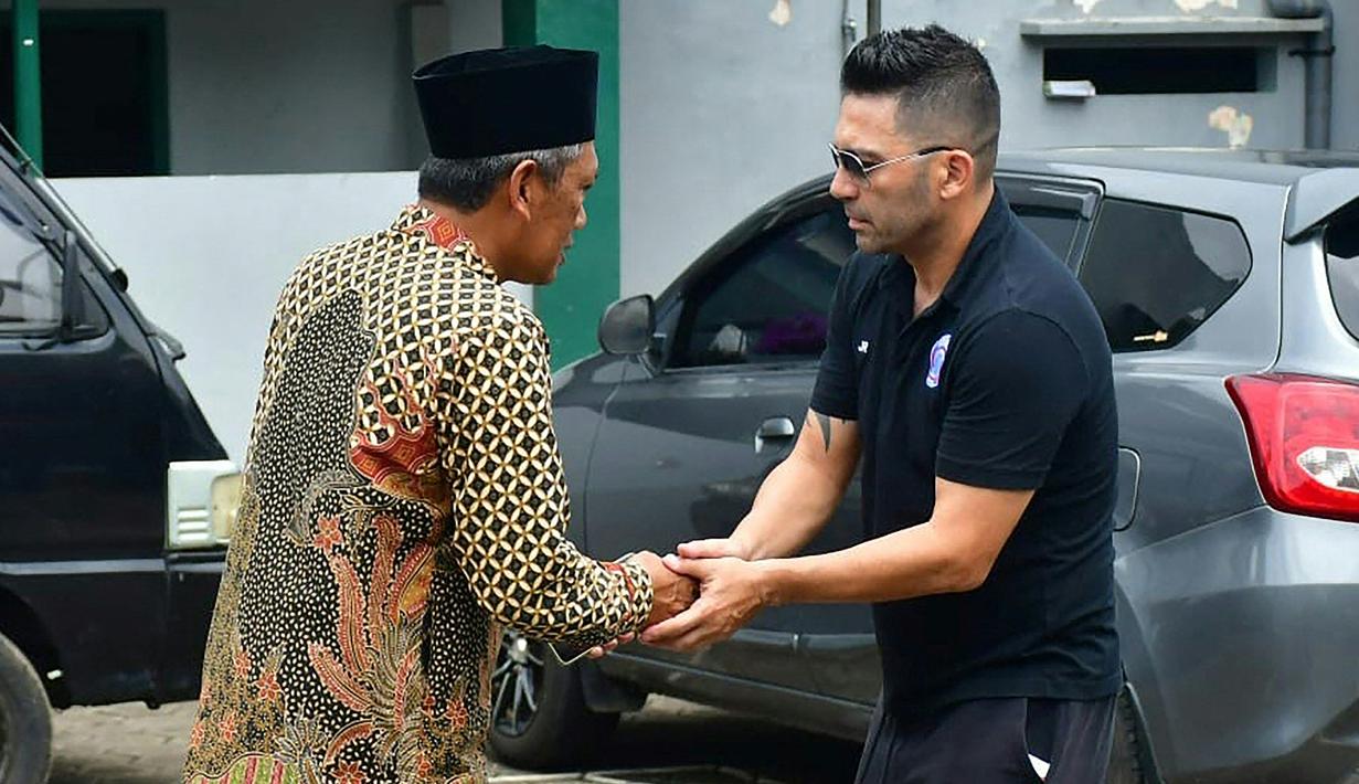 Pelatih Arema FC, Javier Roca menyalami kerabat salah seorang korban Tragedi Kanjuruhan yang merupakan putra pengasuh Pondok Pesantren Miftahul Ulum Atthohirin, Gondanglegi, Malang. (AFP/Putri)