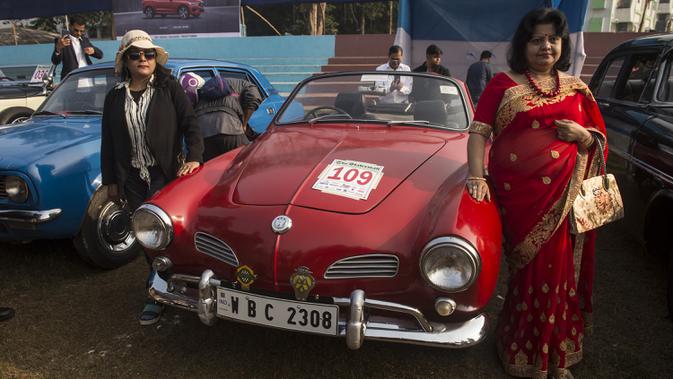 Dua wanita berpose disamping sebuah mobil antik selama acara Reli Mobil Antik Statesman (Statesman Vintage Car Rally) di Kolkata, India (19/1/2020). Lebih dari 180 mobil dan kendaraan roda dua antik ambil bagian dalam reli mobil klasik dan antik pada acara tersebut. (Xinhua/Tumpa Mondal)