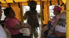 Seorang tentara mengintip ke dalam transportasi umum pada pemeriksaan keamanan yang ditempatkan oleh tentara di Duran, di seberang jembatan dari Guayaquil, Ekuador, Senin, 14 Agustus 2023. (AP Photo/Martin Mejia)