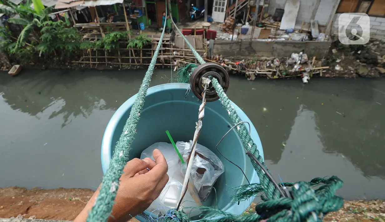 Tak sampai 5 menit, mie ayam ditambah teh dalam plastik pun sampai di tangan pembeli. Selanjutnya, uang pembayaran sebesar Rp 13.000 ribu ditaruh pada ember tersebut. Transaksi selesai saat penjual menarik kembali ember berisi uang. (merdeka.com/Arie Basuki)