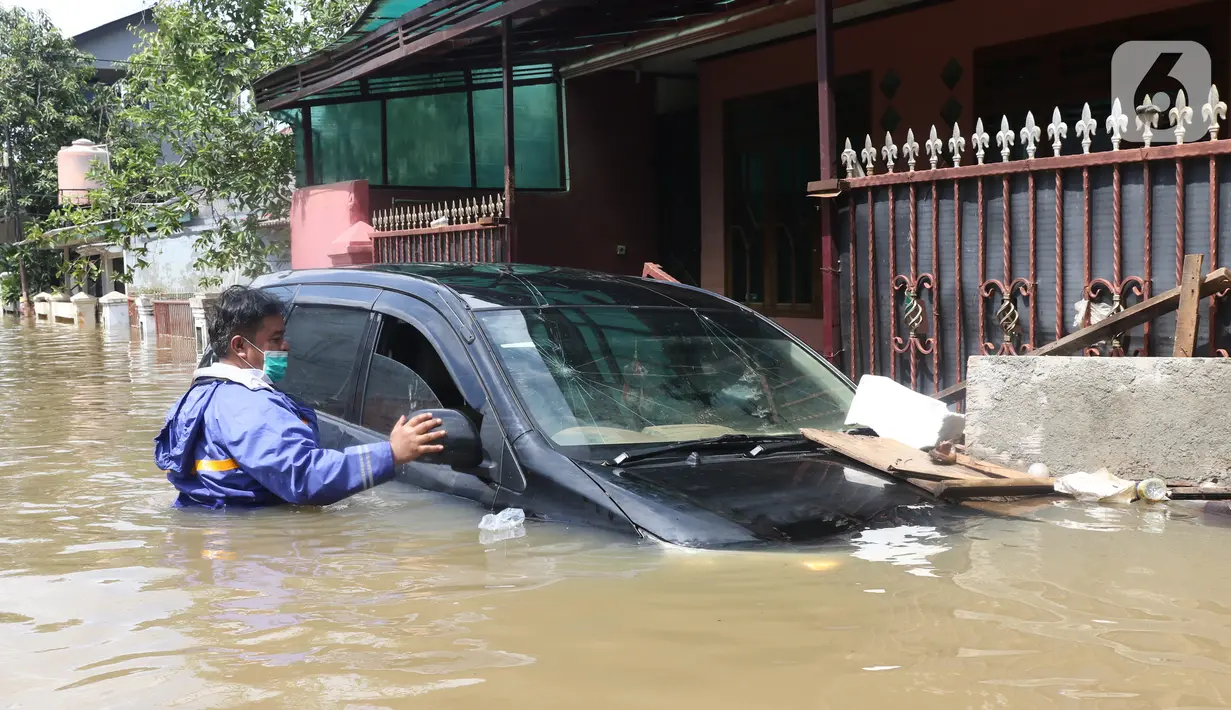 Warga melihat kondisi mobil yang terseret arus banjir di perumah Ciledug Indah, Tangerang, Banten, Kamis (2/1/2020). Sebelumnya, media sosial diramaikan dengan video sejumlah mobil yang terseret arus banjir hingga ratusan meter ke arah dalam perumahan Ciledug Indah. (Liputan6.com/Angga Yuniar)