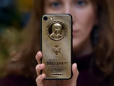 Seorang karyawan dari Caviar Phones memperlihatkan iPhone 7 edisi khusus dengan potret muka Donald Trump di Moskow, Rusia, 14 November 2016. iPhone mewah ini juga ditaburi dengan kristal Svarowsky dan titanium di beberapa sisinya. (Vasily Maximov/AFP)