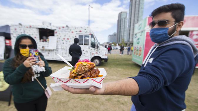 Seorang pria yang mengenakan masker memperlihatkan hidangan ayam goreng di Festival Ayam Goreng, Toronto, Kanada, 20 September 2020. Festival yang digelar di tengah pandemi COVID-19 tersebut berlangsung pada 19-20 September 2020 dengan menghadirkan sekitar 30 jenis ayam goreng. (Xinhua/Zou Zheng)