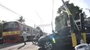 Kereta melintasi perlintasan kereta api di Jalan Duri Kosambi Raya, Jakarta, Rabu (15/1/2020). Warga setempat terpaksa membangun palang secara swadaya dan mengatur lalu lintas akibat perlintasan kereta di dekat Stasiun Rawa Buaya itu belum dipasang palang pintu otomatis. (merdeka.com/Iqbal Nugroho)