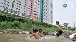 Anak-anak berenang di kubangan air di depan Apartemen Green Pramuka, Jakarta, Rabu (5/2/2020). Keterbatasan ekonomi dan minimnya lahan bermain membuat sekelompok anak sekolah dasar ini memilih berenang di kubangan meskipun mereka tahu air kotor dapat menimbulkan penyakit. (merdeka.com/Iqbal Nugroho)