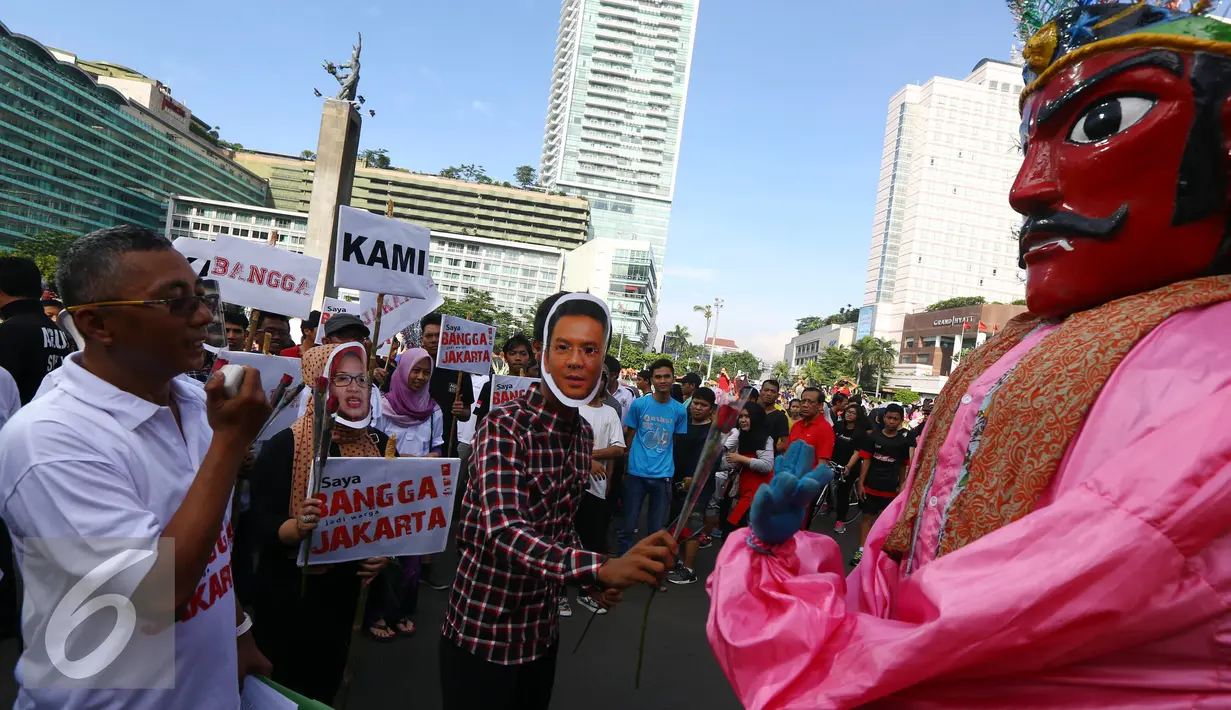 Relawan yang mengenakan topeng Ahok memberikan bunga kepada ondel-ondel saat melakukan aksi kampanye pilkada damai, aman dan sportif di CFD, kawasan Bunderan HI, Jakarta, Minggu (30/10). (Liputan6.com/Johan Tallo)