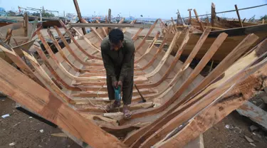 Tukang kayu Pakistan membuat kapal penangkap ikan di sebuah pelabuhan di Karachi (3/4). Pembuatan kapal buatan Pakistan menghasilkan ratusan kapal setiap tahun untuk memenuhi permintaan industri perikanan setempat. (AFP Photo/Asif Hassan)