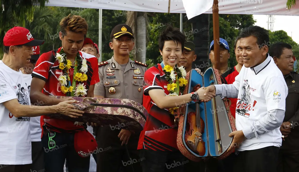 Peraih emas bulutangkis Olimpiade Rio 2016, Tontowi Ahmad dan Liliyana Natsir, mendapat souvenir khas Kudus yang diserahkan Bupati Kudus, Musthofa di alun-alun kota Kudus, Kamis (1/9/2016). (Bola.com/Arief Bagus)