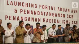 Menkominfo Johnny G. Plate (kelima kiri) bersama sebelas Kementerian dan lembaga negara  usai penandatangan kerja sama pembuatan portal aduan untuk aparatur sipil negara (ASN), Jakarta, Selasa (12/11/2019). Portal ini bisa melaporkan ASN yang diduga terpapar radikalisme. (Liputan6.com/Faizal Fanani)