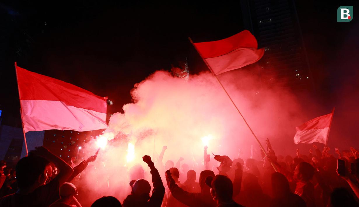 Mereka berkumpul merayakan kemenangan dengan mengibarkan bendera kebanggan Merah-Putih serta menyalakan suar sebagai bentuk rasa suka cita di dalam dunia sepak bola. (Bola.com/M Iqbal Ichsan)