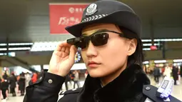 Petugas polisi China mengenakan kacamata dengan sistem pengenalan wajah di Stasiun Kereta Zhengzhou East, China (5/2). Teknologi dalam kacamata ini juga bisa memberitahu para polisi soal terduga pelaku kejahatan yang melarikan diri. (AFP Photo/China Out)