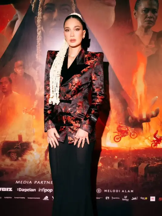 Melengkapi tampilannya dengan gaya modern mengenakan blazer hitam maroon dari desainer @harryhalim. Dipadukan rok hitam panjang polos. [@snap.nuel/@claudianrh]