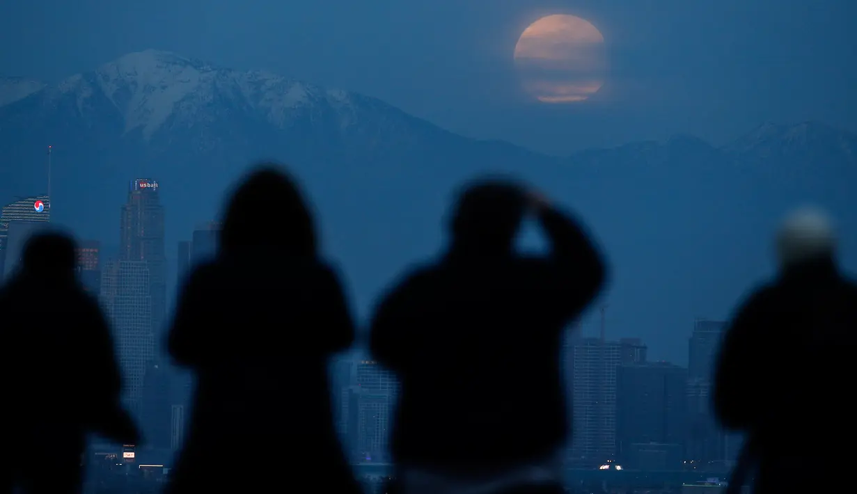 Orang-orang menyaksikan fenomena supermoon atau bulan super dengan latar belakang pusat kota Los Angeles dari Kenneth Hahn Park, Minggu (20/1). Supermoon akhir pekan ini adalah yang pertama terjadi pada tahun 2019 ini. (AP/Ringo H.W. Chiu)