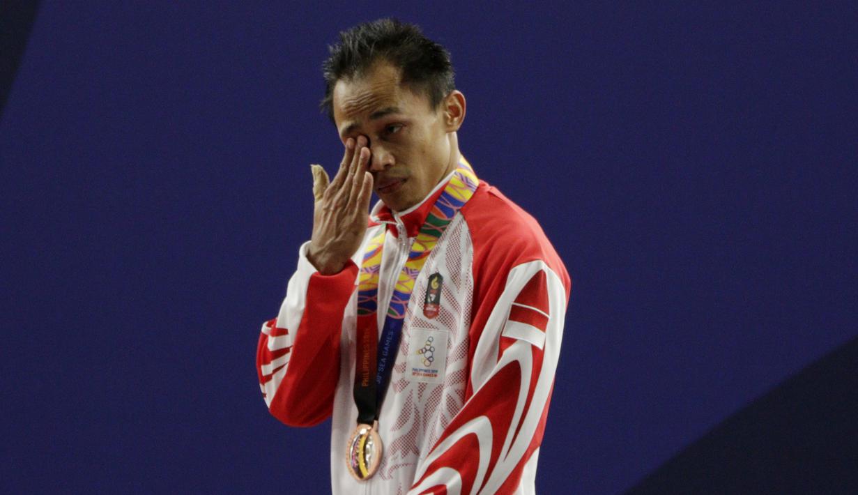 Lifter Suratman menangis saat naik podium usai mendapatkan medali perunggu SEA Games 2019 cabang angkat besi nomor 55 kg di Stadion Rizal Memorial, Manila, Minggu (1/12). Dirinya meraih perak dengan total angkatan 250 kg. (Bola.com/M Iqbal Ichsan)