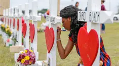 Siswi SMA Santa Fe, Jai Gillard menulis pesan pada salib di depan sekolah mereka di Texas, Amerika Serikat, Senin (21/5). Penembakan di sekolah Santa Fe beberapa waktu lalu menewaskan 10 orang. (Steve Gonzales/Houston Chronicle via AP)
