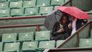 Dua orang penonton menunggu hujan reda  pada laga antara Richard Gasquet dan Kei Nishikori pada turnamen Prancis Terbuka 2016 di Roland Garros, (28/5/2016). (AFP/Thomas Samson)