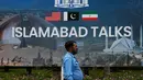 Diketahui, Amerika Serikat dan Iran saat ini berada dalam masa gencatan senjata selama dua minggu yang mulai berlaku sejak Rabu, 8 April 2026. Tampak dalam foto, seorang petugas polisi berjalan melewati papan reklame mengenai negosiasi Amerika Serikat dan Iran, di luar pusat fasilitasi media di Islamabad, Pakistan, Sabtu, 11 April 2026. (AP Photo/Anjum Naveed)