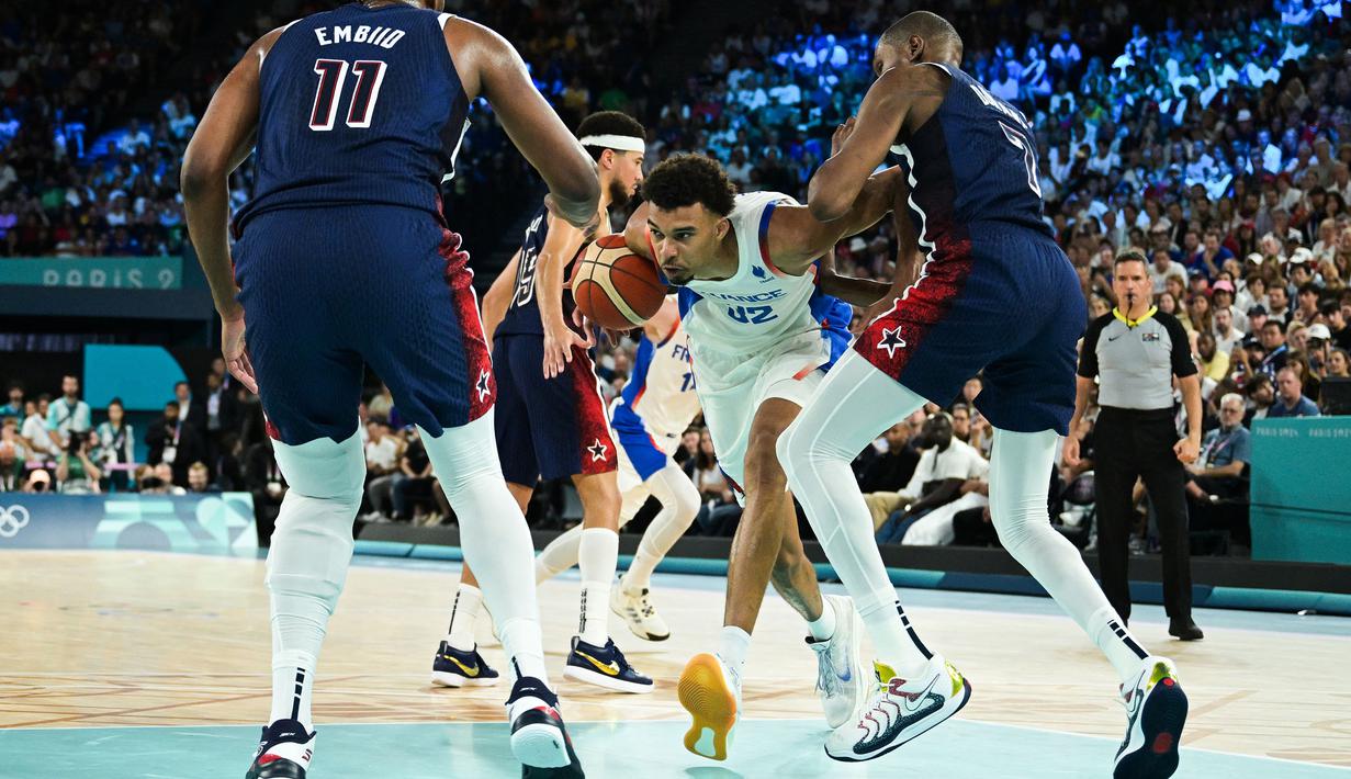Pebasket Prancis, Victor Wembanyama (tengah) berusaha melewati penjagaan sejumlah pebasket Amerika Serikat pada pertandingan final Olimpiade Paris 2024 yang berlangsung di Bercy Arena, Paris, Prancis, Minggu (11/08/2024) dini hari WIB. (AFP/Damien Meyer)