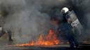 Polisi anti huru-hara saat mencoba memadamkan api dari para demonstran di Athena, Yunani, (12/11/2015). Semua aktifitas perkantoran, publik dan penerbangan ditutup karena aksi ini. (REUTERS/Michalis Karagiannis)