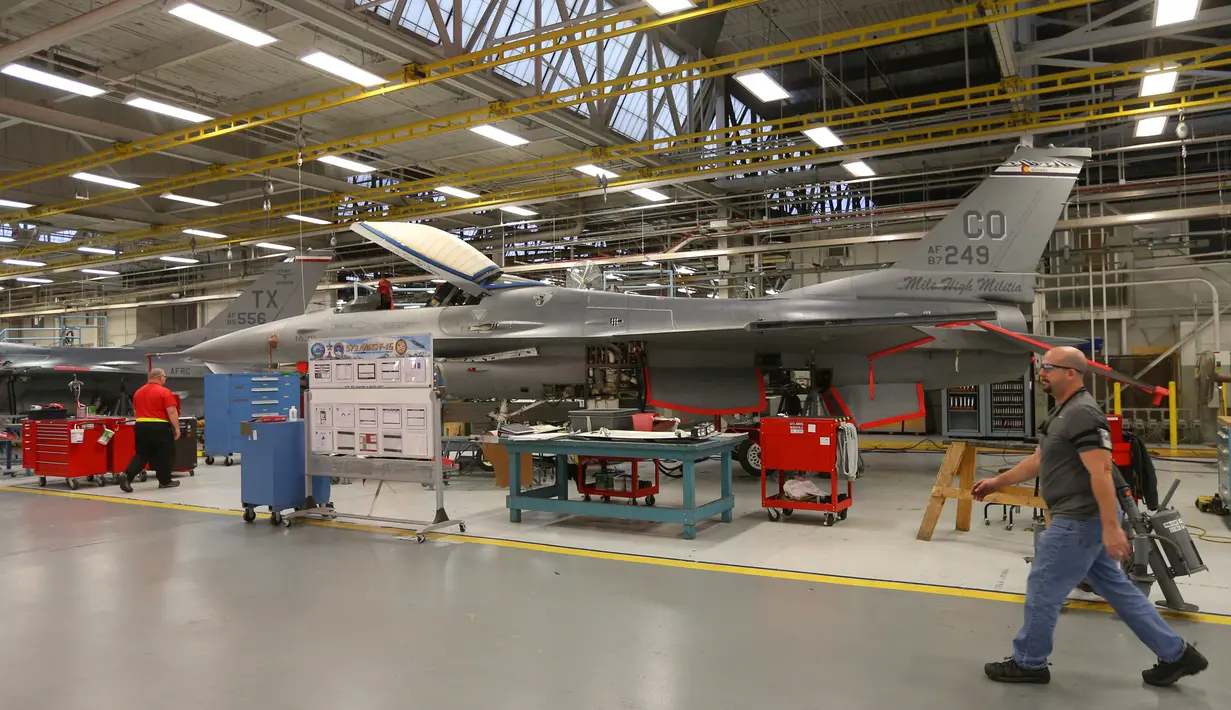 Mekanik berjalan melintas di dekat pesawat F-16 Falcon di pangkalan Angkatan Udara Hill di Ogden, Utah (20/12). Di pangkalan udara ini jet temput A-10 dan F-16 dilakukan perbaikan dan diperiksa kesiapannya. (George Frey/Getty Images/AFP)