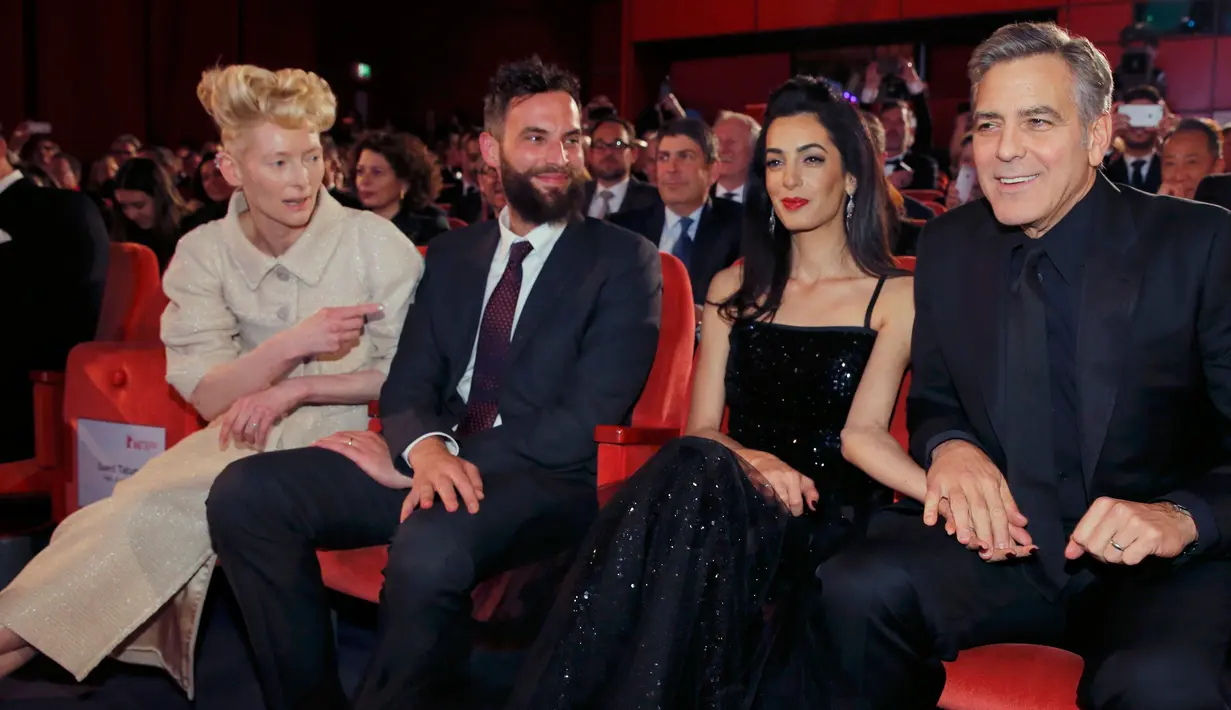 Aktor AS, George Clooney (kanan) terlihat menggenggam tangan istrinya, Amal Alamuddin, saat menghadiri pemutaran film "Hail, Caesar!" pada pembukaan Berlin International Film Festival ke-66 di Berlin, Jerman, Kamis (11/2). (REUTERS/Fabrizio Bensch)