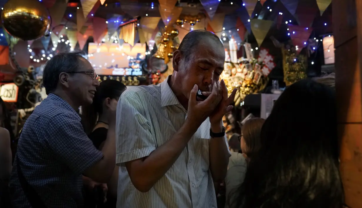 Seorang pria memainkan harmonika di sebuah bar di Golden Gai di distrik Shinjuku, Tokyo (26/7/2019). Kawasan Ini terdiri dari enam jalanan sempit yang menghubungkan lorong yang lebih sempit yang hanya cukup dilewati satu orang. (AP Photo / Jae C. Hong)