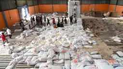 Sebelumnya, pada akhir bulan lalu, terjadi penjarahan gudang Bulog yang berada di Kecamatan Sarudik, Kota Sibolga. Tampak dalam foto, warga desa menerima bahan pangan pokok yang didistribusikan di tengah upaya bantuan dari gudang beras pemerintah di Sarudik, Tapanuli Tengah, Provinsi Sumatra Utara, pada Rabu 3 Desember 2025. (YT Hariono/AFP)