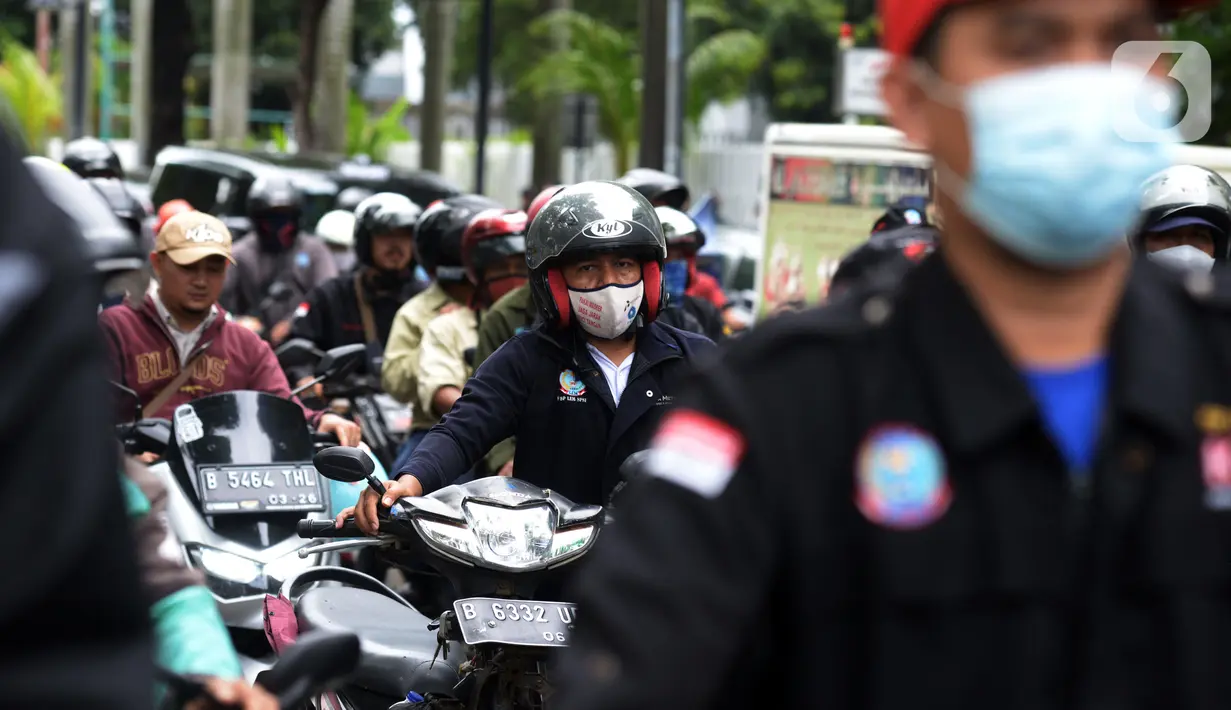 Buruh mendorong sepeda motor mereka saat melakukan aksi unjuk rasa di kawasan Patung Kuda, Jakarta, Rabu (10/11/2021). Buruh menuntut pemerintah untuk mencabut UU Cipta Kerja dan meminta Presiden Joko Widodo atau Jokowi untuk mundur. (merdeka.com/Imam Buhori)