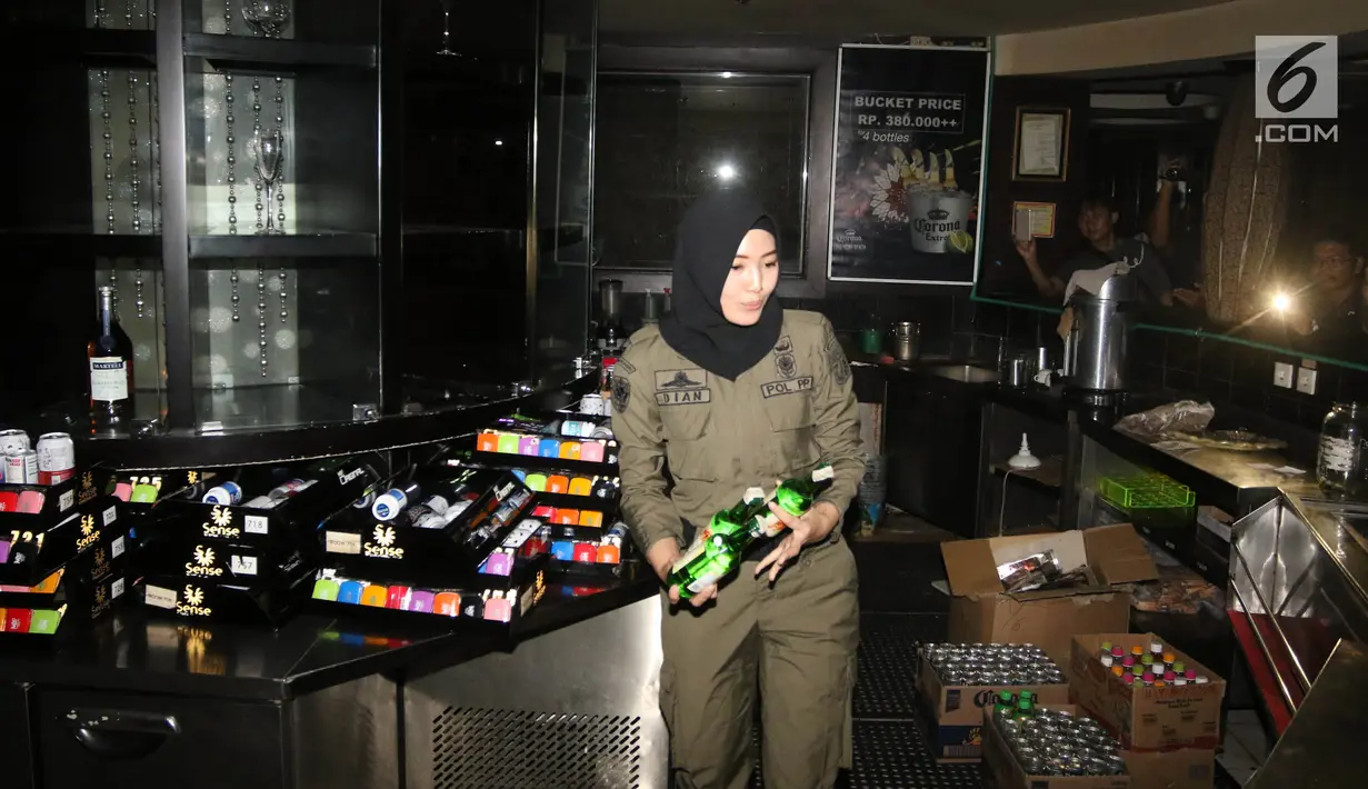 Petugas Satpol PP wanita mengamankan sejumlah botol minuman keras di Sense Karaoke, Mangga Dua Square, Jakarta, Kamis (19/4). (Liputan6.com/Arya Manggala)