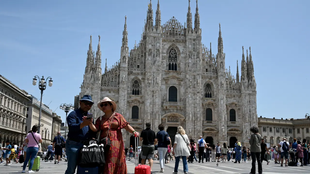 Wisatawan bersiap berpose untuk 'selfie' di depan Katedral Duomo di Milan pada 6 Juli 2023. GABRIEL BOUYS / AFP