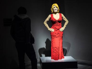 Seseorang berdiri di dekat patung "Courtney Red" yang terbuat dari susunan balok lego pada pameran Art of the Brick di Turin, Italia, Kamis (15/11). Pameran tersebut menampilkan berbagai patung lego karya seniman AS, Nathan Sawaya. (MARCO BERTORELLO/AFP)