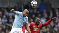Striker Manchester United, Romelu Lukaku, duel udara dengan bek Manchester City, Vincent Kompany, pada laga Premier League di Stadion Etihad, Sabtu (7/4/2018). Manchester City takluk 2-3 dari Manchester United. (AP Photo/Matt Dunham)