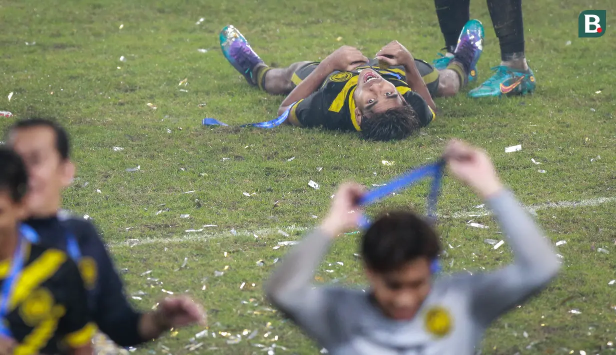 Pemain Timnas Malaysia U-19, Adam Farhan Mohd Faizal (kiri) tergeletak usai diduga mengalami kram saat timnya merayakan juara Piala AFF U-19 2022 di Stadion Patriot Candrabhaga, Bekasi, Jumat (15/07/2022). (Bola.com/Bagaskara Lazuardi)
