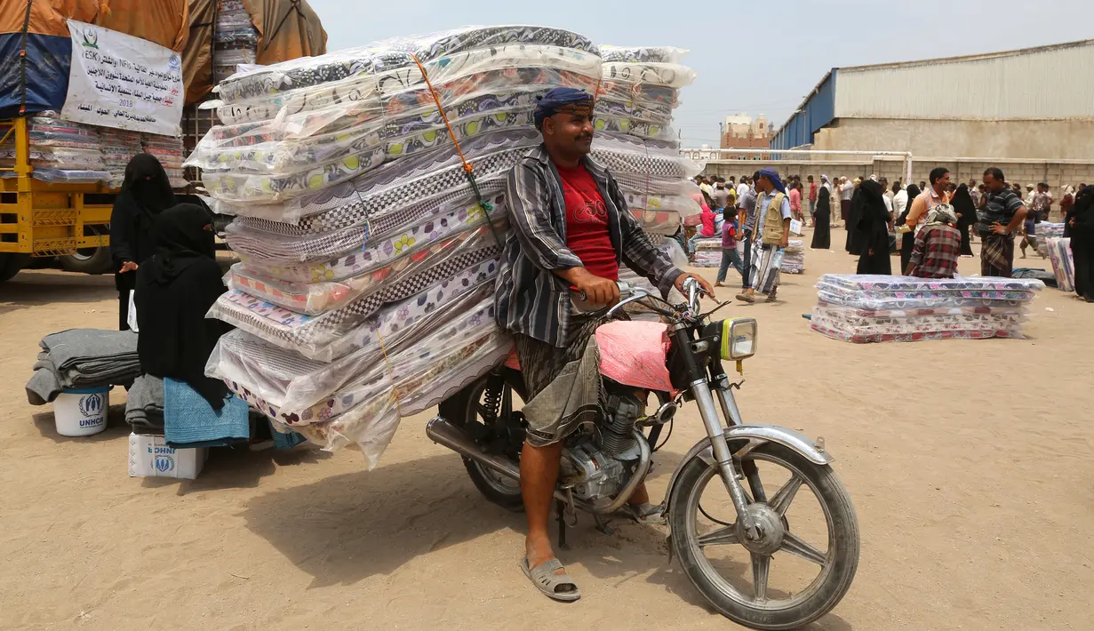 Seorang pria membawa tumpukan alas tidur yang diberikan oleh UNHCR di kota pesisir Hodeidah, Yaman (11/4). Hodeidah adalah pelabuhan terbesar di Yaman yang menjadi tempat masuk sebagian besar bantuan kemanusiaan. (AFP Photo/Abdo Hyder)