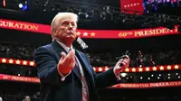 Presiden Amerika Serikat, Donald Trump melemparkan pena ke arah kerumunan setelah menandatangani perintah eksekutif selama parade perdana di dalam Capital One Arena, Washington, DC pada 20 Januari 2025. (Jim WATSON/AFP)