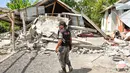 Petugas keamanan desa memeriksa rumah yang roboh akibat gempa di Lombok, NTB, Minggu (29/7). Data sementara BPBD Provinsi NTB mencatat, gempa bumi tektonik 6.4 SR itu mengakibatkan 10 orang meninggal dunia dan puluhan rumah rusak. (AFP/Aulia AHMAD)
