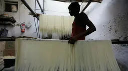 Pekerja India menggantung helai bihun untuk dikeringkan di sebuah pabrik di Ahmadabad pada 16 Mei 2019. Bihun sangat diminati di kalangan muslim India karena merupakan menu favorit yang kerap disuguhkan saat berbuka puasa bersama dengan buah-buahan manis. (AP Photo/Ajit Solanki)