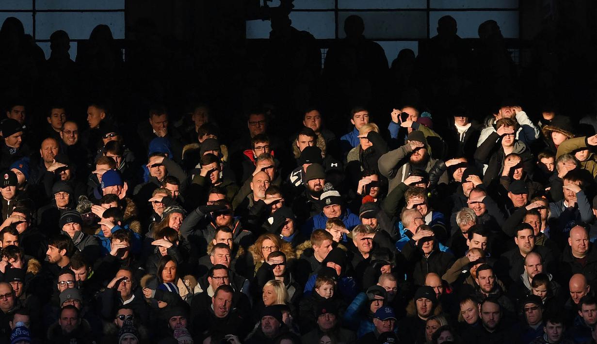 Para suporter tampak silau saat menyaksikan laga Liga Inggris antara Everton melawan Southampton di Stadion Goodison Park, Inggris, Senin (2/1/2017). Everton menang 3-0 atas Southampton. (AFP/Paul Ellis)