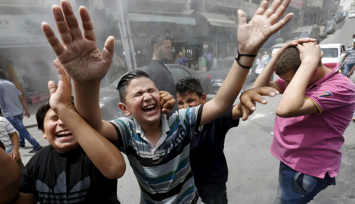 Anak-anak bersorak ketika personel dinas Kota Amman menyemprot mereka dengan sprinkler air untuk mengurangi efek dari gelombang panas di Yordania, Senin(3/8/2015). (REUTERS/Muhammad Hamed)