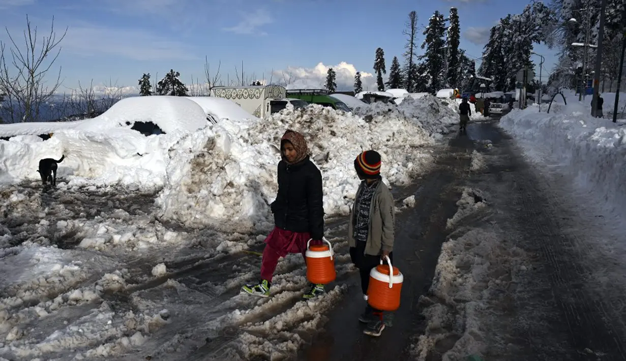 Penjual telur berjalan melewati kendaraan yang tertutup salju di sepanjang jalan Bukit Murree, Pakistan, 9 Januari 2022. Sebanyak 22 wisatawan tewas saat sekitar 1.000 kendaraan terjebak salju tebal di Bukit Murree. (Aamir QURESHI/AFP)