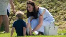 Kate Middleton merapikan sepatu Pangeran George saat menghadiri acara amal Kerajaan Inggris bertajuk Maserati Royal Charity Polo Trophy di Beaufort Polo Club, Gloucestershire, Minggu (10/6). Pangeran William ambil bagian dalam kegiatan tersebut (AP Photo)