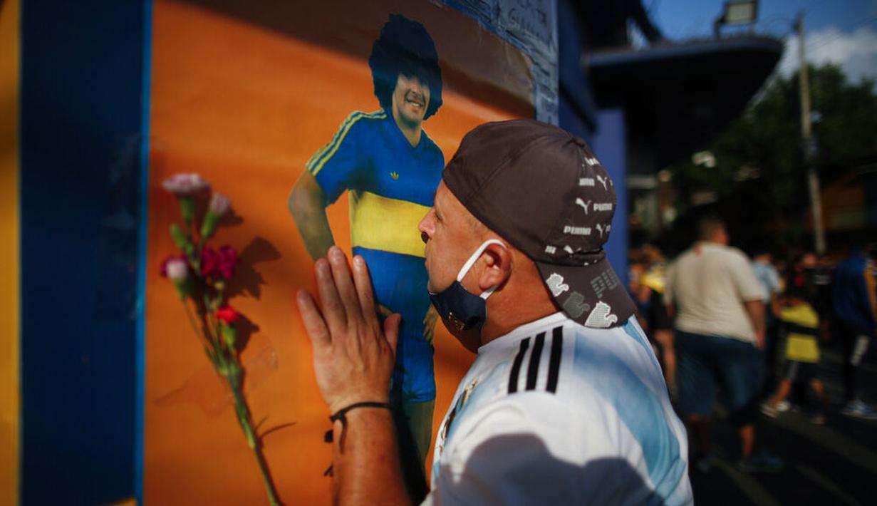 Seorang fans mencium poster Diego Maradona di Buenos Aires, Argentina, Rabu (25/11/2020). legenda sepak bola Argentina itu meninggal dunia pada usia 60 tahun setelah menderita serangan jantung. (AP/Natacha Pisarenko)